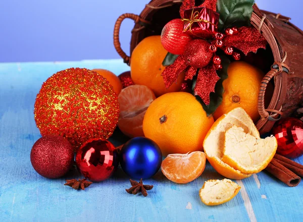 Mandarinas navideñas y juguetes navideños en cesta sobre mesa de madera sobre fondo azul — Foto de Stock