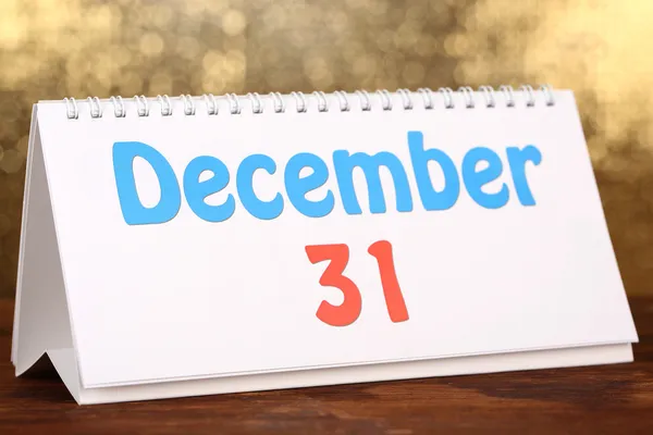 Calendário de ano novo na mesa de madeira, no fundo dourado brilhante — Fotografia de Stock