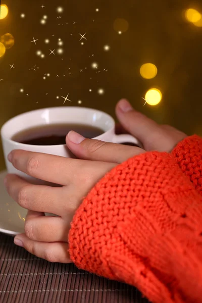 Mani che tengono tazza di bevanda calda, primo piano, su sfondo luminoso — Foto Stock