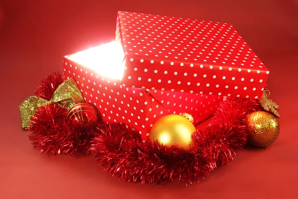 Gift box with bright light on it on red background — Stock Photo, Image