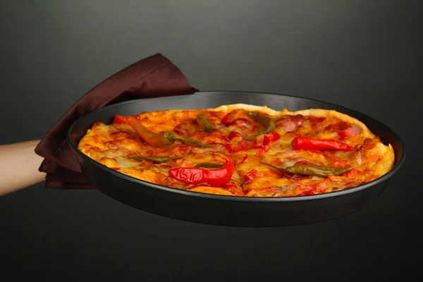 Main tenant pizza pepperoni dans une casserole sur fond gris — Photo