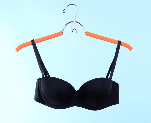 Elegant bra on hanger on blue background — Stock Photo, Image