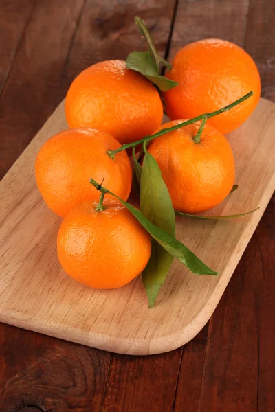 Sweet tangerines with leaves, on wooden background — Stock Photo, Image