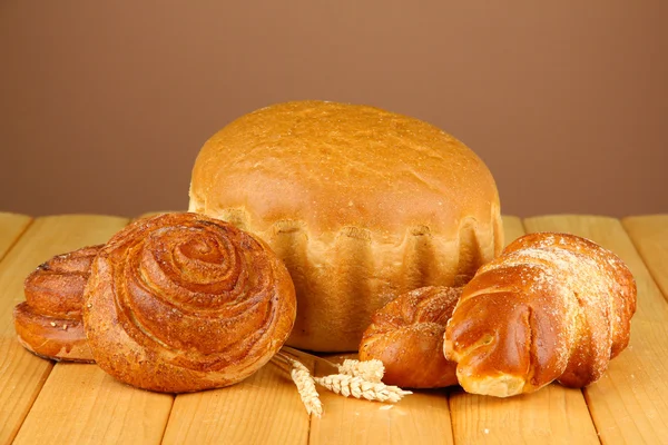 Samenstelling met brood en broodjes op houten tafel, op een achtergrond met kleur — Stockfoto