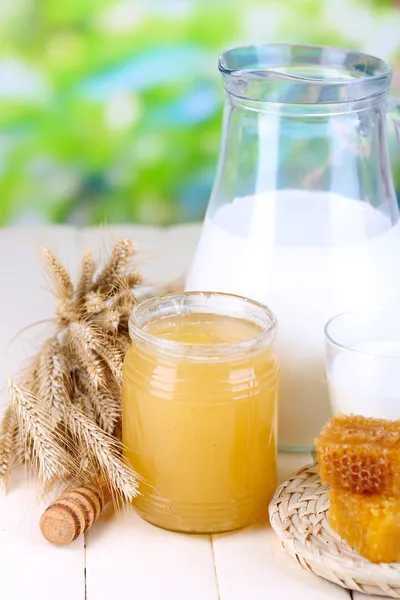Мед и молоко на деревянном столе на естественном фоне — стоковое фото