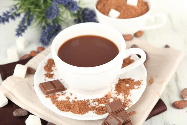 Cacao en polvo en taza en servilleta sobre mesa de madera — Foto de Stock