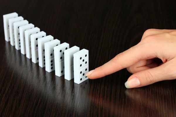 Hand pushing dominoes on wooden background — Stock Photo, Image
