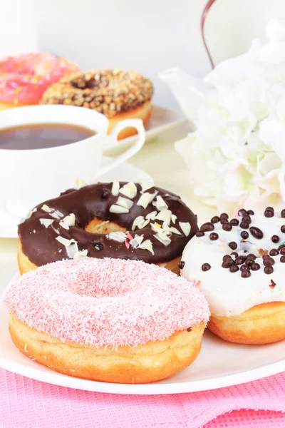 Donat manis dengan secangkir teh di atas meja pada latar belakang cahaya — Stok Foto