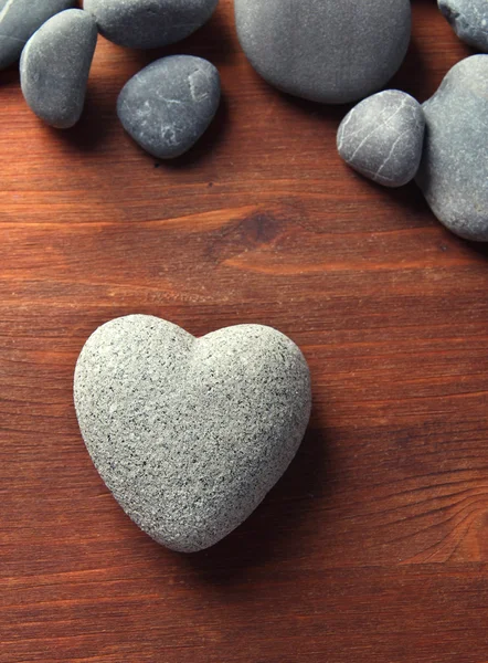 Pedra cinzenta em forma de coração, sobre fundo de madeira — Fotografia de Stock