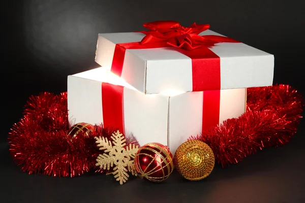 Gift box with bright light on it on dark grey background — Stock Photo, Image