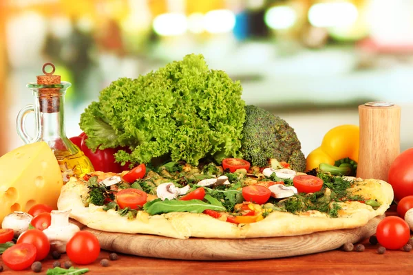 Вкусная вегетарианская пицца и овощи на деревянном столе — стоковое фото