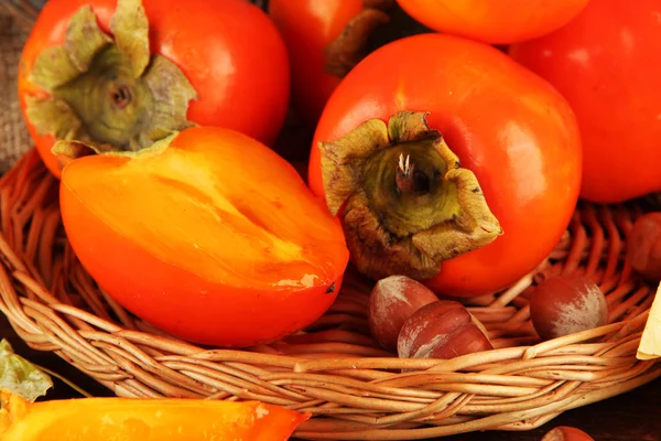 Ripe persimmons with nuts on table close up — Stock Photo, Image