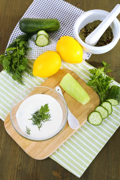 Cucumber yogurt in glass bowl, on color napkin, on wooden background — Stock Photo, Image