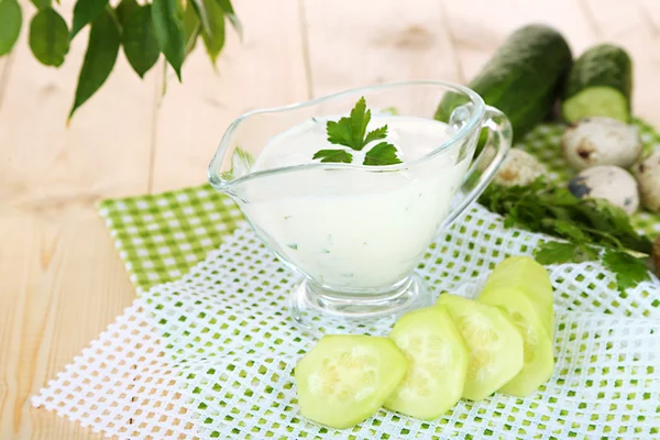 Komkommer yoghurt in glazen kom, op kleur servet, op houten achtergrond — Stockfoto