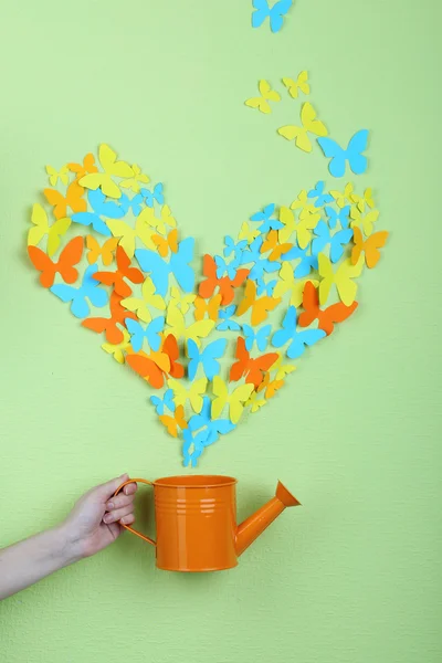 Farfalle di carta volare fuori annaffiatoio su sfondo parete verde — Foto Stock