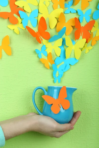 Papierschmetterlinge fliegen aus Krug auf grünem Wandhintergrund — Stockfoto