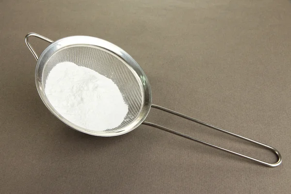 Azúcar en polvo en tamiz metálico sobre fondo gris — Foto de Stock