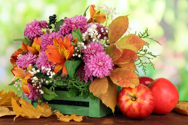 Композиция цветов в ящике с яблоками на столе на ярком фоне — стоковое фото