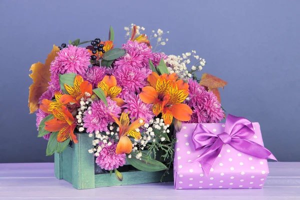Tabloda gri arka plan üzerinde hediye ile sandık bileşiminde çiçekler — Stok fotoğraf