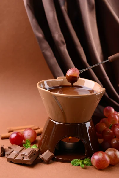 Chocolate fondue with fruits, on brown background — Stock Photo, Image