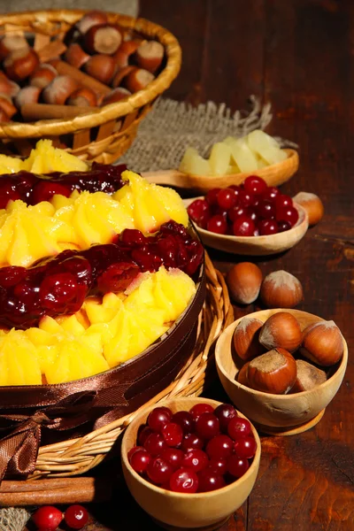 Lezzetli meyveli ev yapımı pasta ile meyve ve fındık, kahverengi ahşap masa — Stockfoto