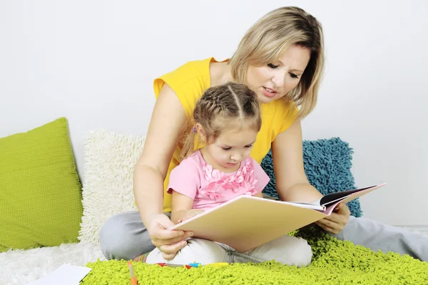 Little girl with mom read book in bed — Stock Photo, Image