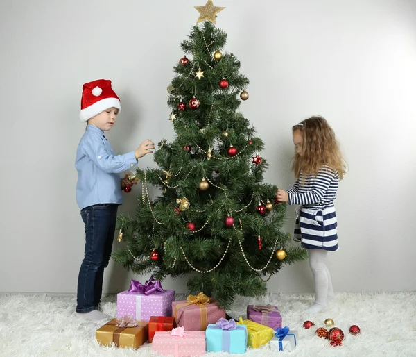 Kinderen versieren kerstboom met kerstballen op kamer — Stockfoto