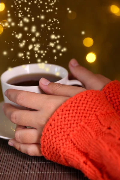 Hands holding mug of hot drink, close-up, on bright background — Stock Photo, Image