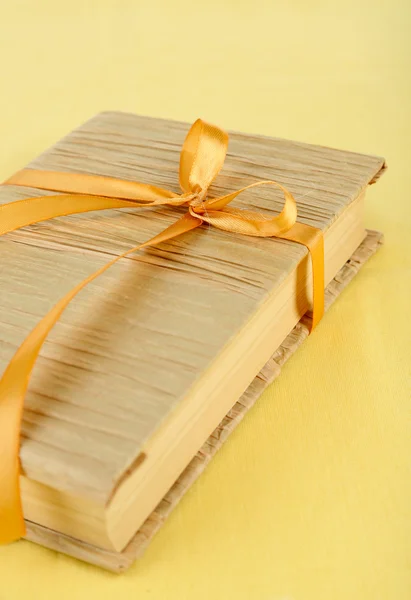 Book wrapped with color ribbon, on color background — Stock Photo, Image