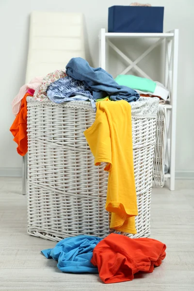 Cesta de lavandaria completa no chão de madeira em casa fundo interior — Fotografia de Stock