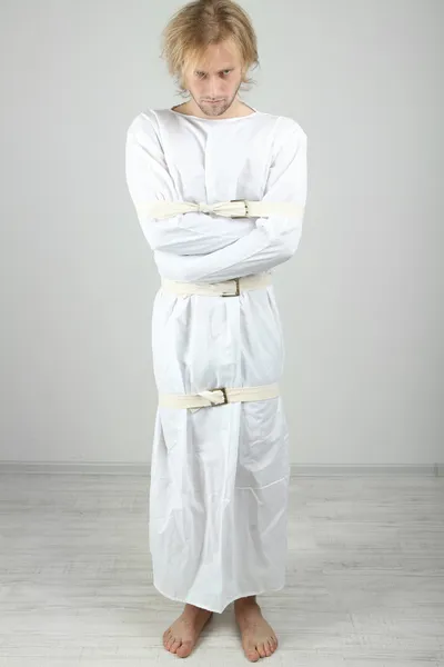 Hombre mentalmente enfermo con camisa de fuerza sobre fondo gris — Foto de Stock