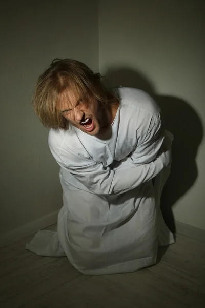 Homem mentalmente doente em camisa de força no canto do quarto — Fotografia de Stock