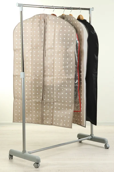 Clothes in cases for storing on hangers, on gray background — Stock Photo, Image