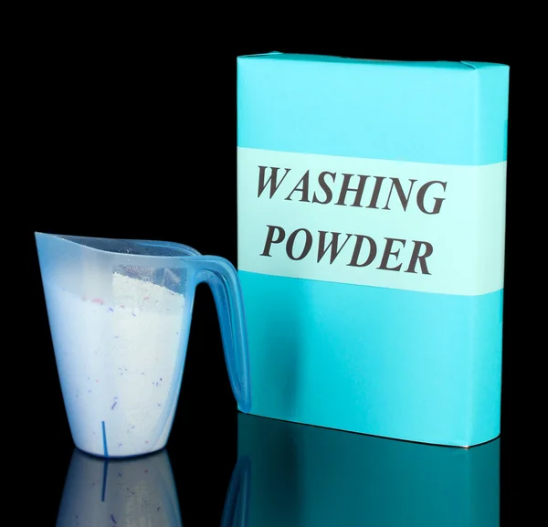 Box of washing powder with blue measuring cup, isolated on black — Stock Photo, Image