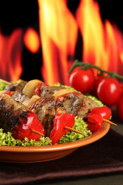 Tasty grilled meat and vegetables on plate, on fire background — Stock Photo, Image