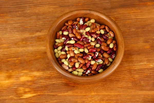 Dřevěná miska s fazolemi na dřevěné pozadí — Stock fotografie