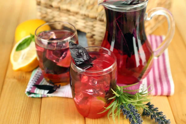 Citronnade au basilic rouge en cruche et verre, sur table en bois, sur fond lumineux — Photo