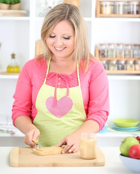 रसोई में खुश मुस्कुरा रही महिला सैंडविच तैयार कर रही — स्टॉक फ़ोटो, इमेज