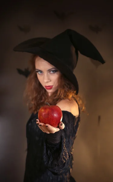 Halloween heks met apple op donkere achtergrond — Stockfoto