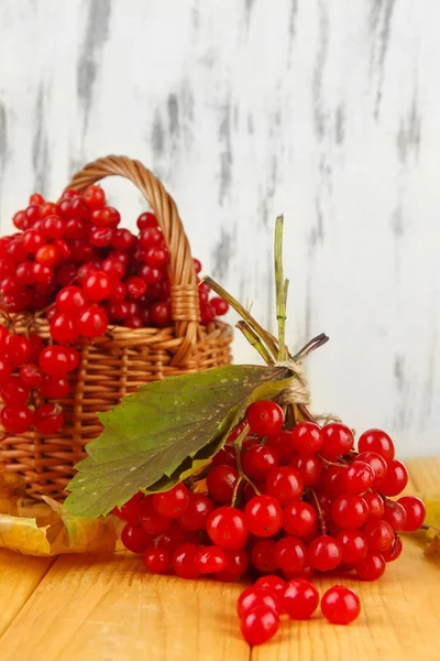 Bagas vermelhas de viburnum na cesta na mesa no fundo de madeira — Fotografia de Stock