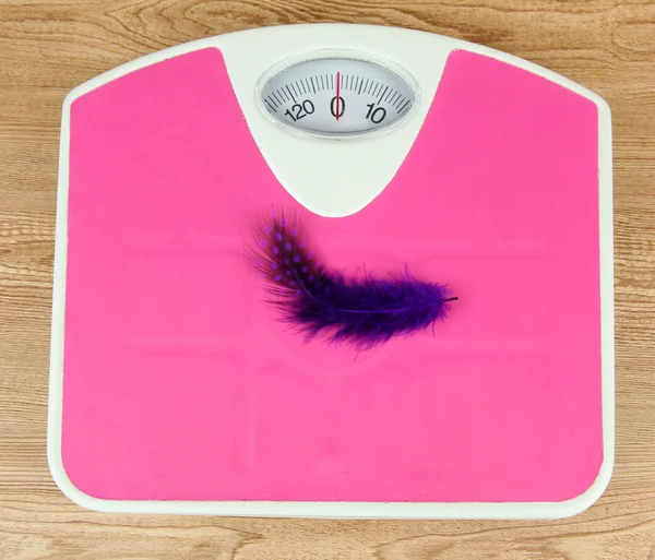 Feather on scales on table close-up — Stock Photo, Image