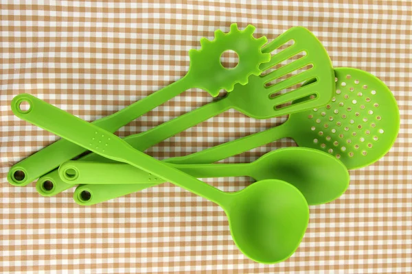 Plastic kitchen utensils on fabric background — Stock Photo, Image