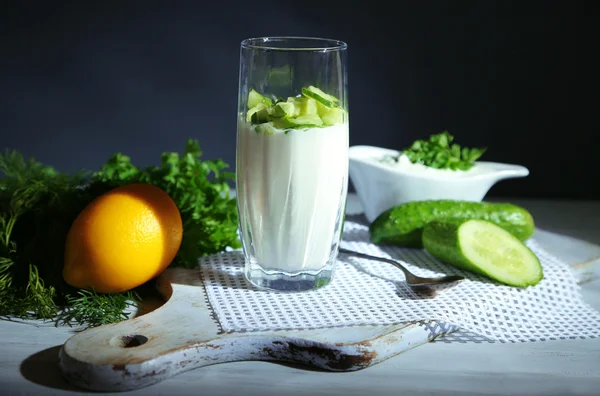 Cam, ahşap arka plan üzerinde renkli peçete üzerinde salatalık yoğurt — Stok fotoğraf