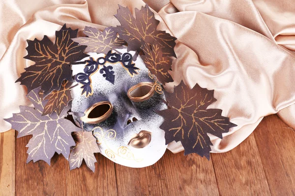 Maske auf goldenem Stoff auf Holzgrund — Stockfoto