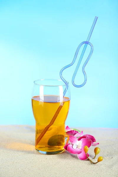 Glass of cocktail, on sand, on bright background — Stock Photo, Image