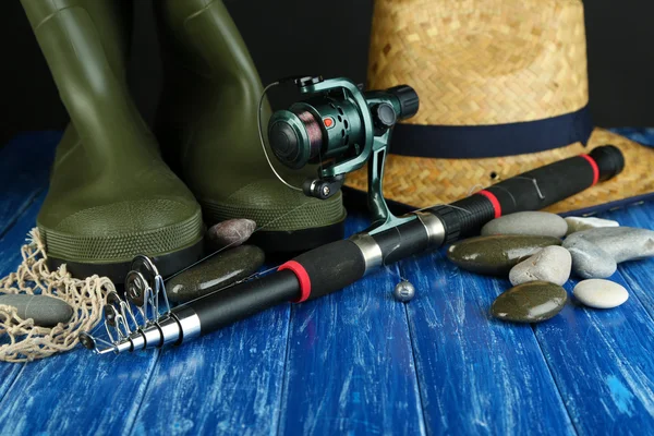 Fishing rod, gumboots and hat on wooden table close-up — Stock Photo, Image