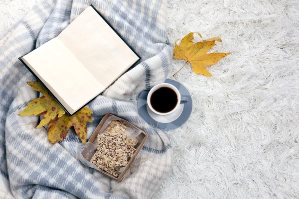 Composition with warm plaid, book, cup of hot drink on color carpet background — Stock Photo, Image