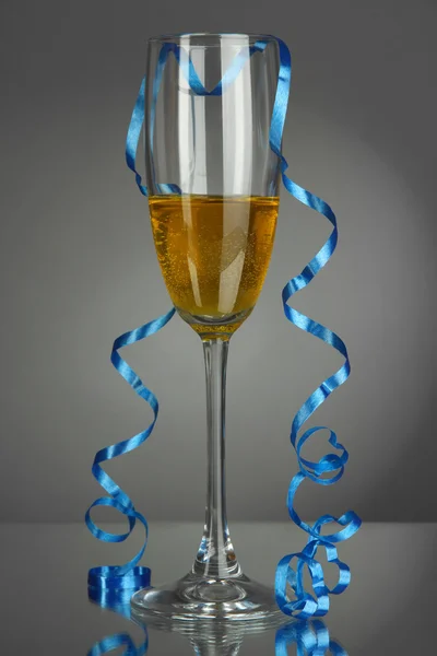 Copa de champán y serpentina después de la fiesta sobre fondo gris —  Fotos de Stock
