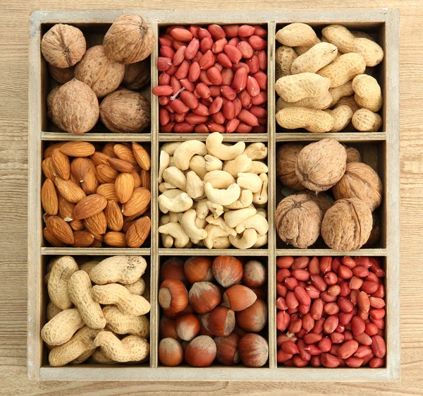Ассортимент вкусных орехов в деревянной коробке на столе — стоковое фото