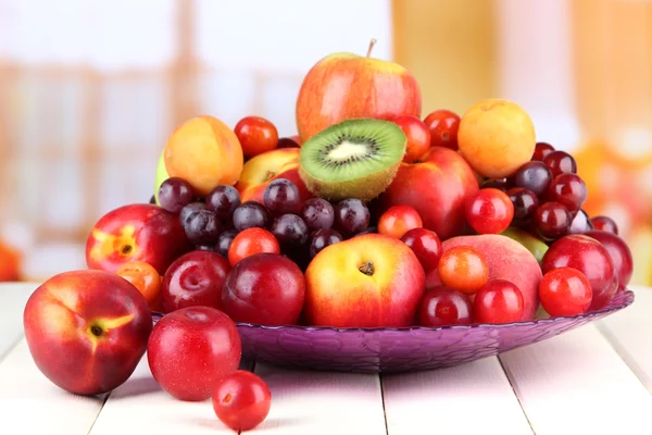 Assortment of juicy fruits on wooden table, on bright background — Stock Photo, Image